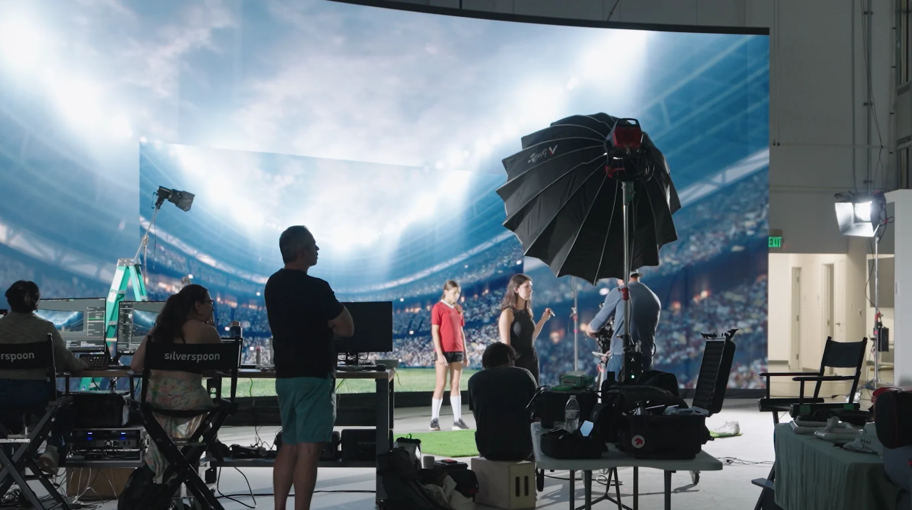The Colligo set: a curved LED volume wall playing a stadium, crew working in front of it